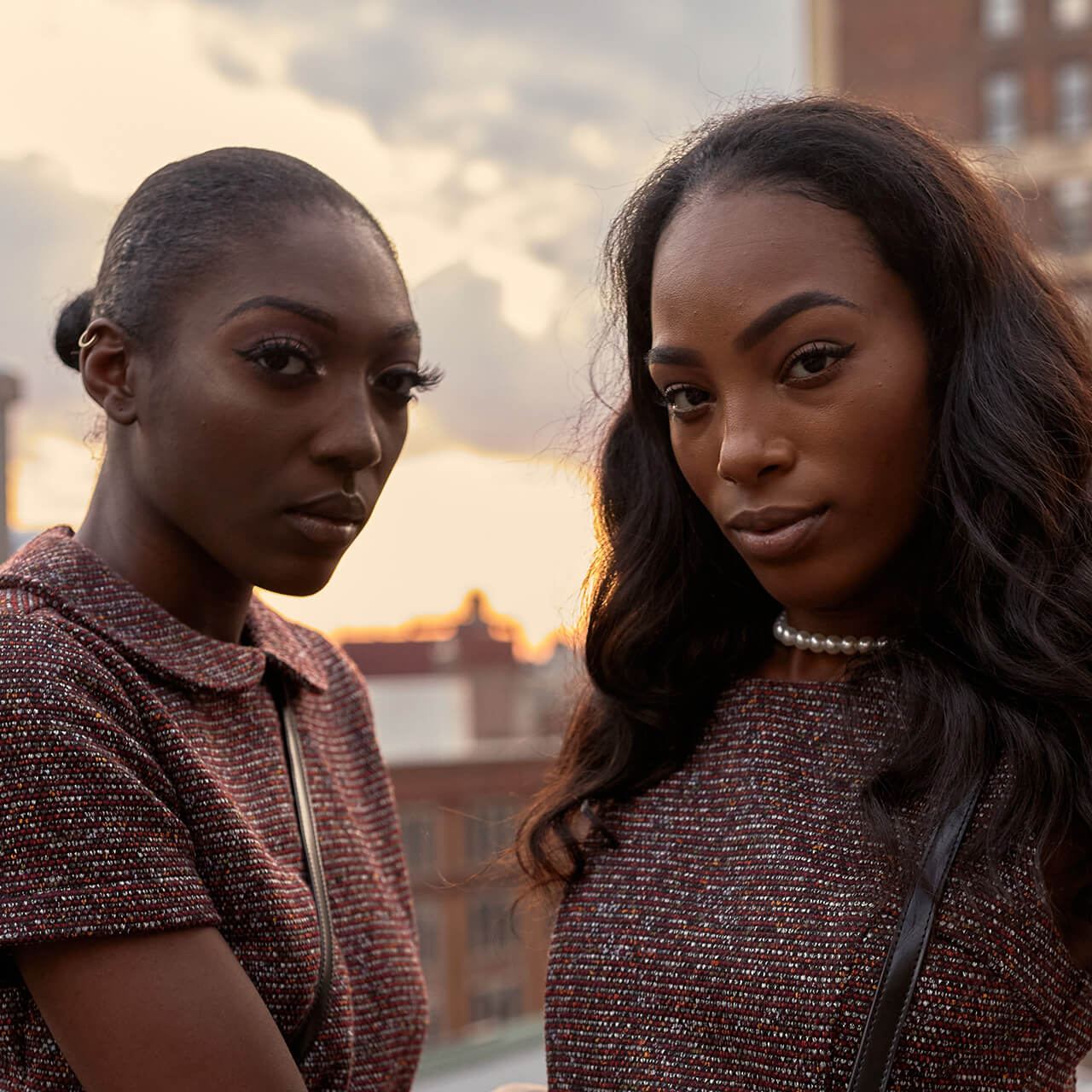 Before: Two women in patterned tops on a rooftop at sunset