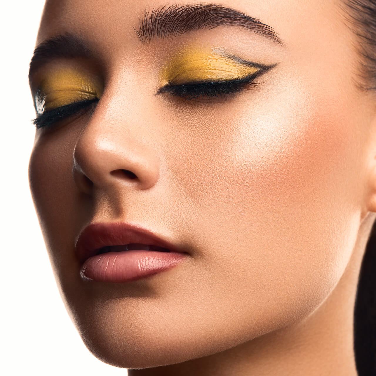 After: Close-up of a woman’s face with yellow eyeshadow and winged eyeliner
