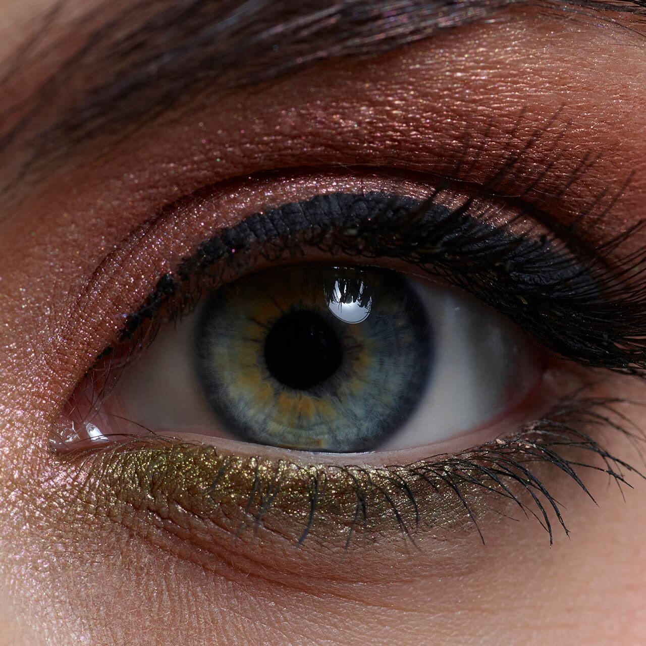 Before: Extreme close-up of an eye with golden-green glitter eyeshadow